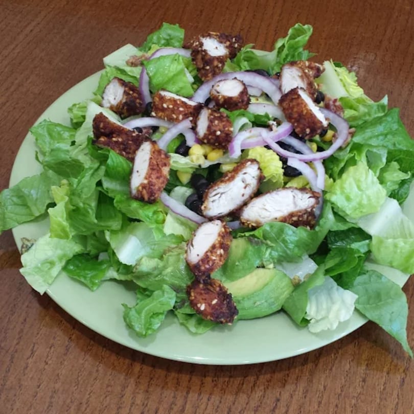 Lola's Chicken Shack salad with fried chicken, lettuce, red onion, corn, black beans, and avocado.